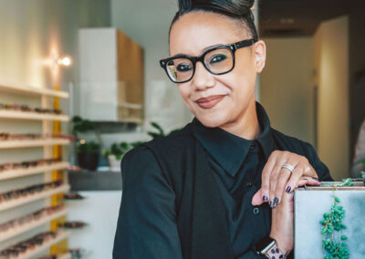 Female standing inside the store wearing some black frame eyeglasses