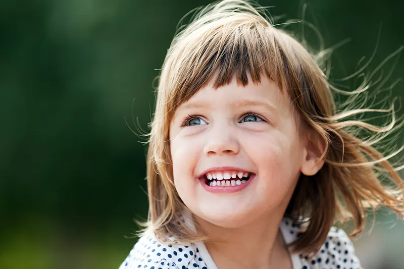 a little girl smiling outdoors