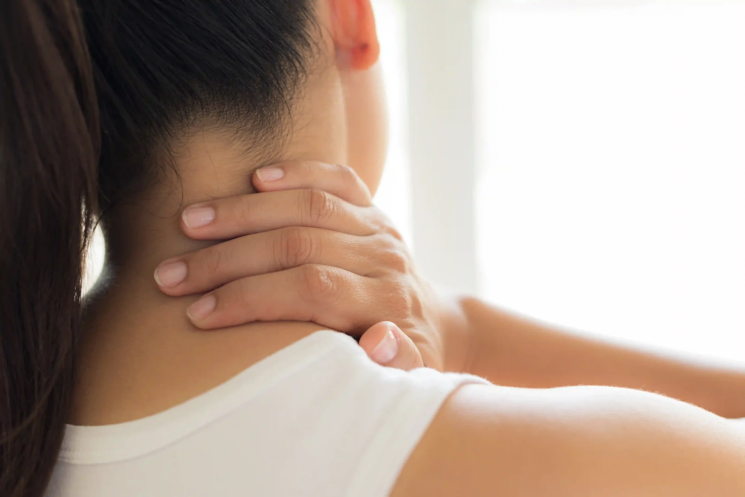 woman placing hand on her neck and shoulder area